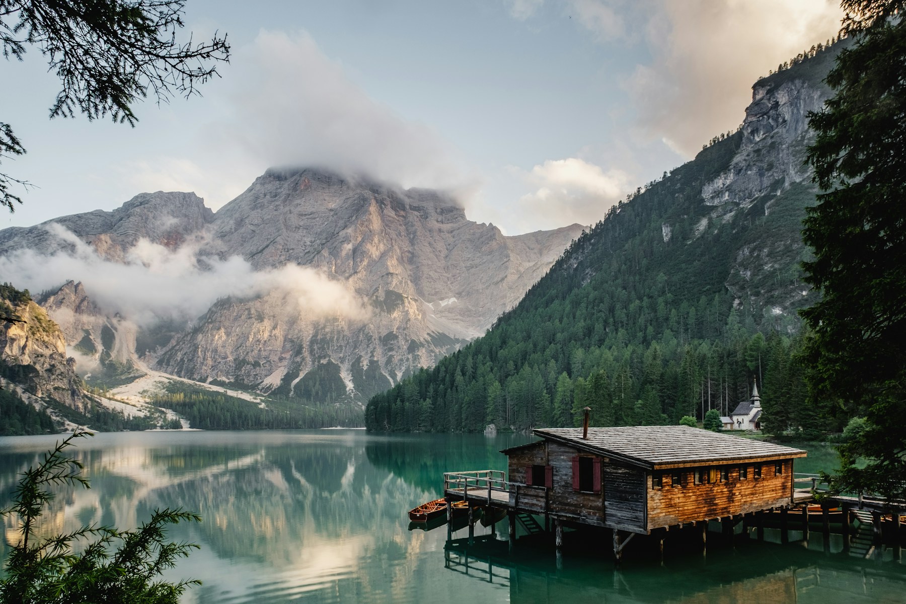 Mountain lake framed by forest and drifting clouds